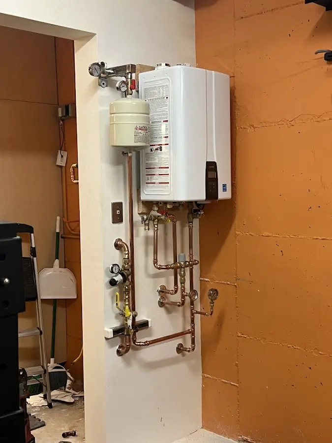 Plumbing technician inspecting water heater connections in Troy